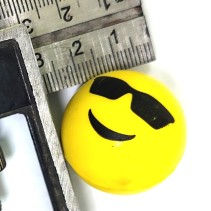 Pomiar średnicy żółtej piłeczki skoczka emoji przy użyciu metalowej linijki